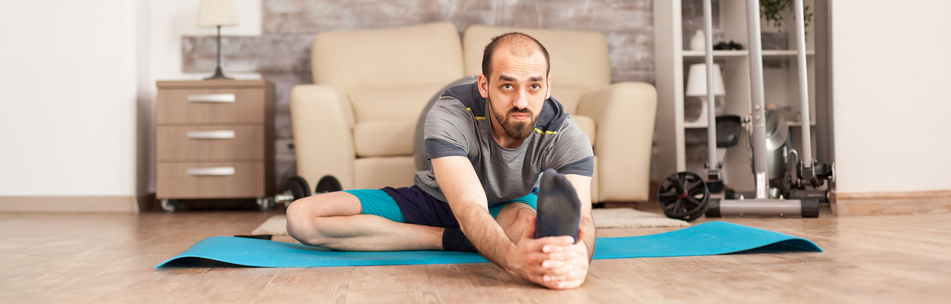 Mann macht Stretching-Übungen im Homeoffice